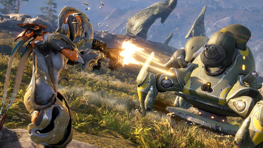 A third-person action gameplay screenshot from Warframe, showing a Warframe character firing a gun with bright muzzle flashes at a mechanical, green-and-yellow enemy robot in an open, grassy landscape with rocky formations under a bright sky.